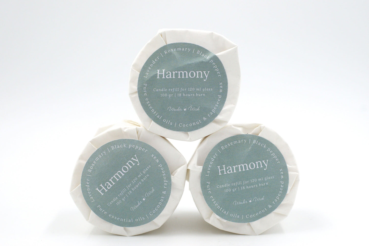 Three Harmony candle refills for 120 ml glass, stacked to display eco-conscious packaging with 18-hour burn time details, and ingredients like lavender, rosemary, and black pepper.
