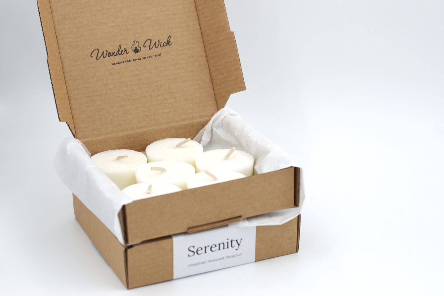 Open cardboard box of six Serenity tealight refills with essential oils. Natural, hand-poured tealights infused with grapefruit, rosewood, and bergamot for a mood boosting experience.