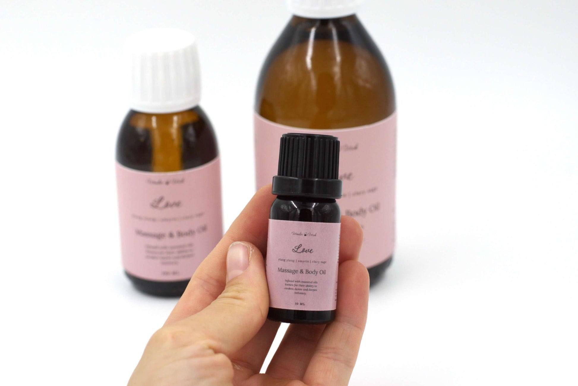 10ml bottle of Love aphrodisiac massage oil, held in a hand, showcasing its blend of ylang-ylang, amyris, and clary sage essential oils. Created to awaken desire and deepen intimacy.