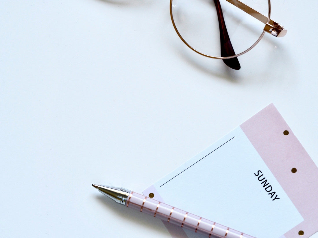A minimalist flat lay of a Sunday planner with a pen and glasses, symbolising a Sunday reset routine.