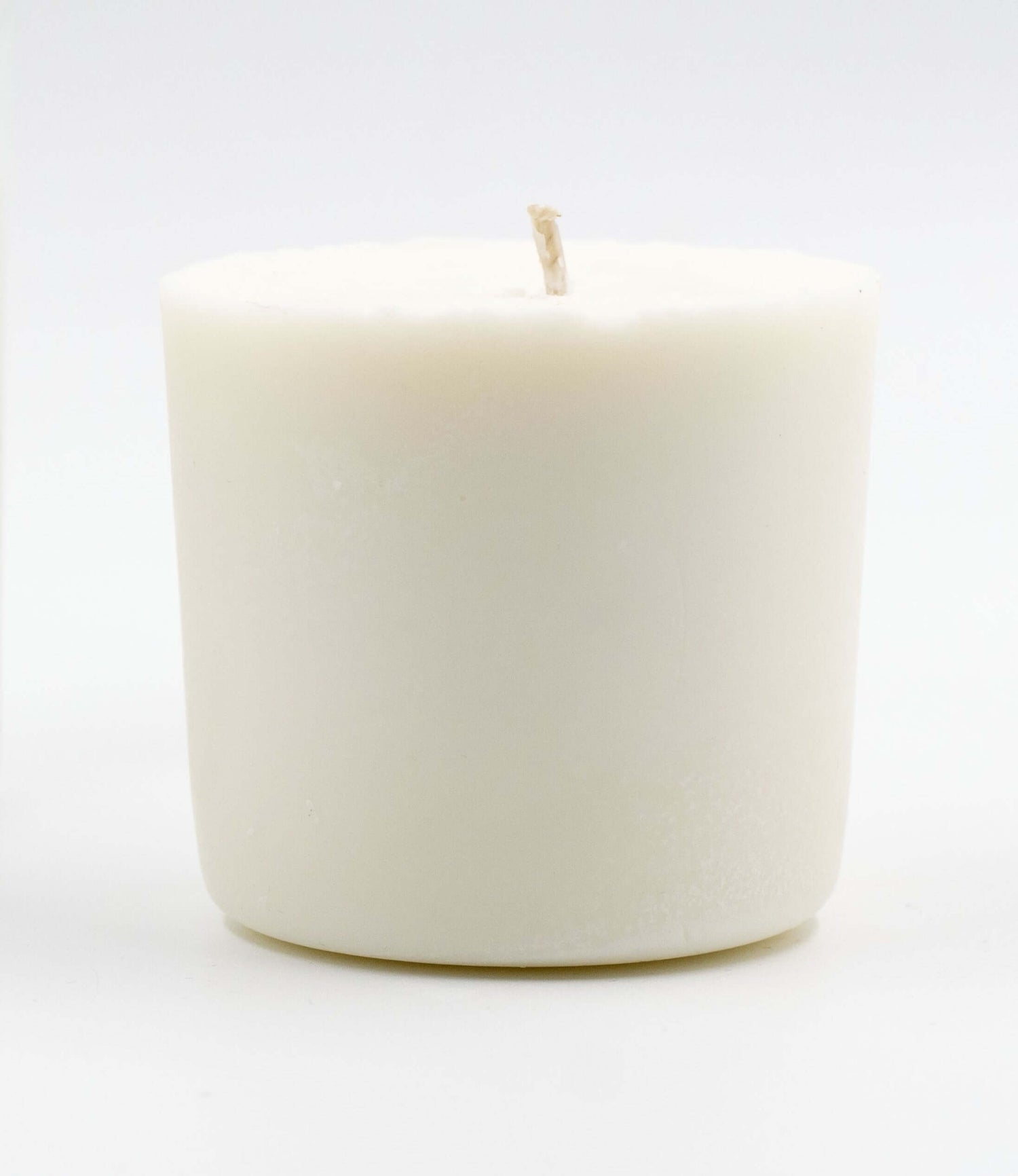 Close-up of a white candle refill, showcasing a simple, minimalist design without a container, ready to fit into an existing candle jar.