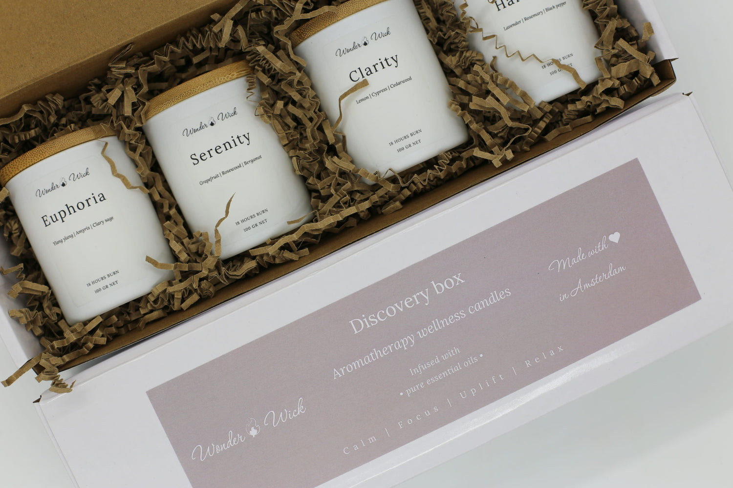 Wonder Wick wellness gift box with four essential oil candles in Euphoria, Serenity, Clarity, and Harmony blends, packed in eco-friendly shredded paper inside a white box with soft branding.