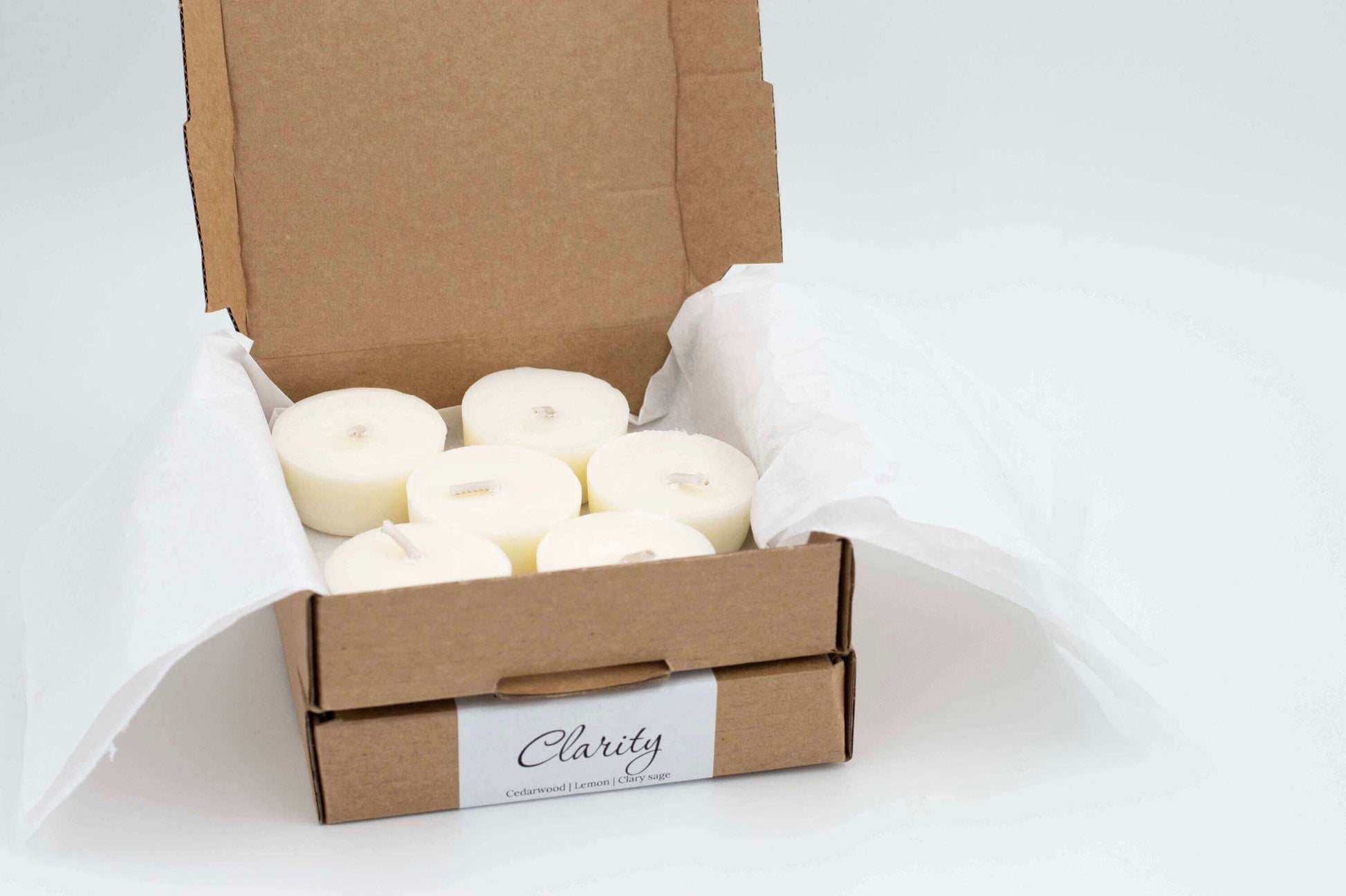 6-pack of Clarity tea light candles made with cedarwood, lemon, and clary sage, natural and refillable tealights, packaged in an eco-friendly box with tissue paper.