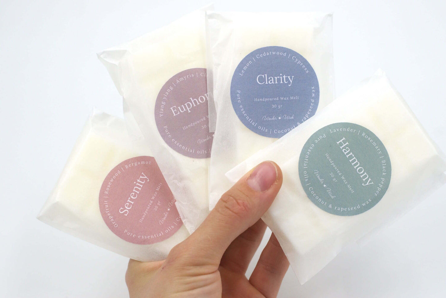 Four packaged wax melts labeled as Clarity, Euphoria, Serenity, and Harmony, showcasing a collection of aromatherapy scents in eco-friendly glassine wraps.