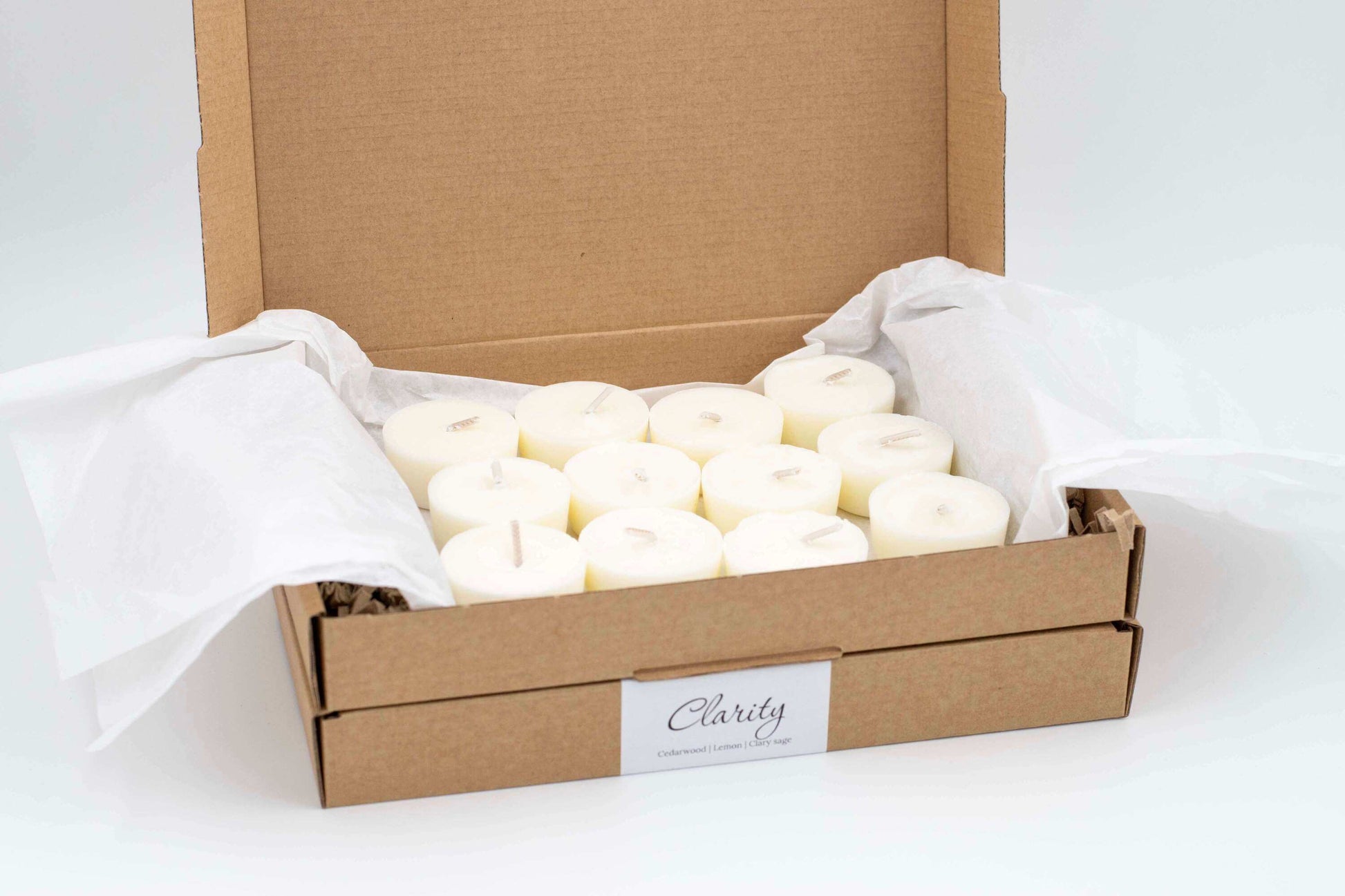 12-pack of Clarity aromatherapy tealights with cedarwood, lemon, and clary sage, eco-friendly and vegan, in a recyclable cardboard box."