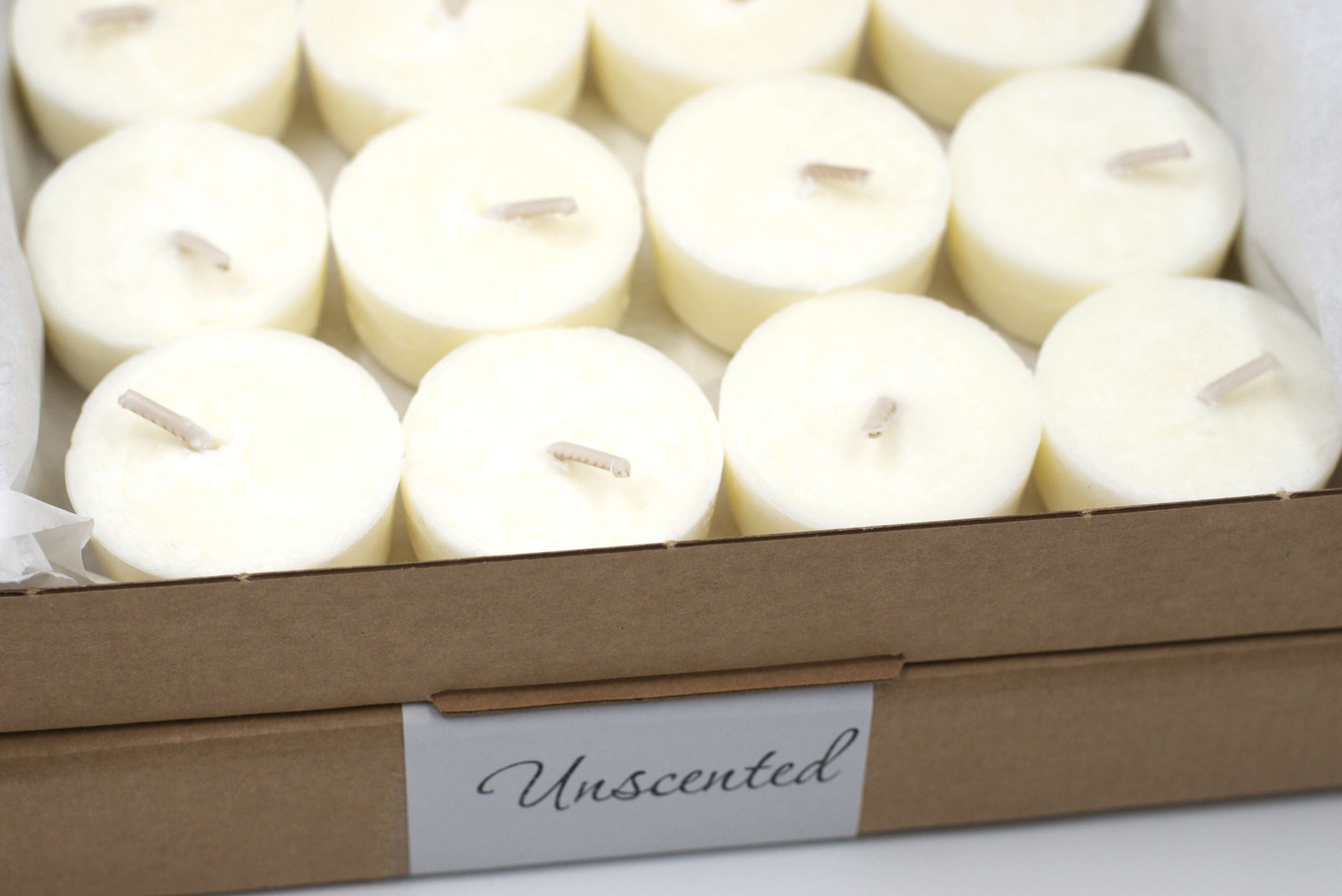 Detailed view of twelve unscented tea light candles in a cardboard box, showcasing eco-friendly and vegan tea light refills for aromatherapy and home use.