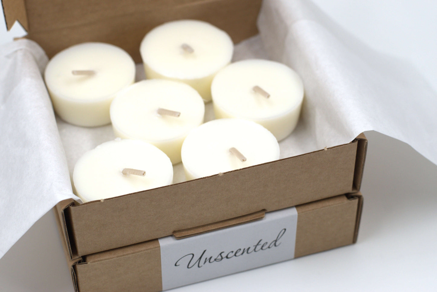 Close-up of six unscented tea light candles arranged in a cardboard box, designed as eco-friendly refills for tea light holders.