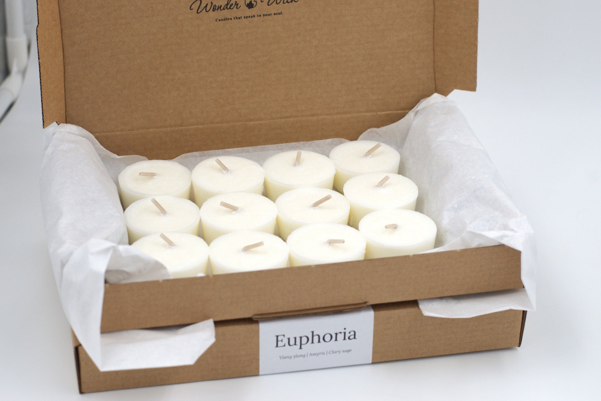 Euphoria tealight refills, pack of 12, in an eco-friendly cardboard box. Hand-poured with essential oils featuring ylang ylang, amyris, and clary sage for a calming aromatherapy experience.