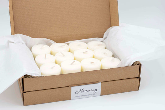 12-pack of Harmony essential oil tealights featuring lavender, rosemary, and black pepper, eco-friendly and vegan, in a cardboard box with tissue paper.