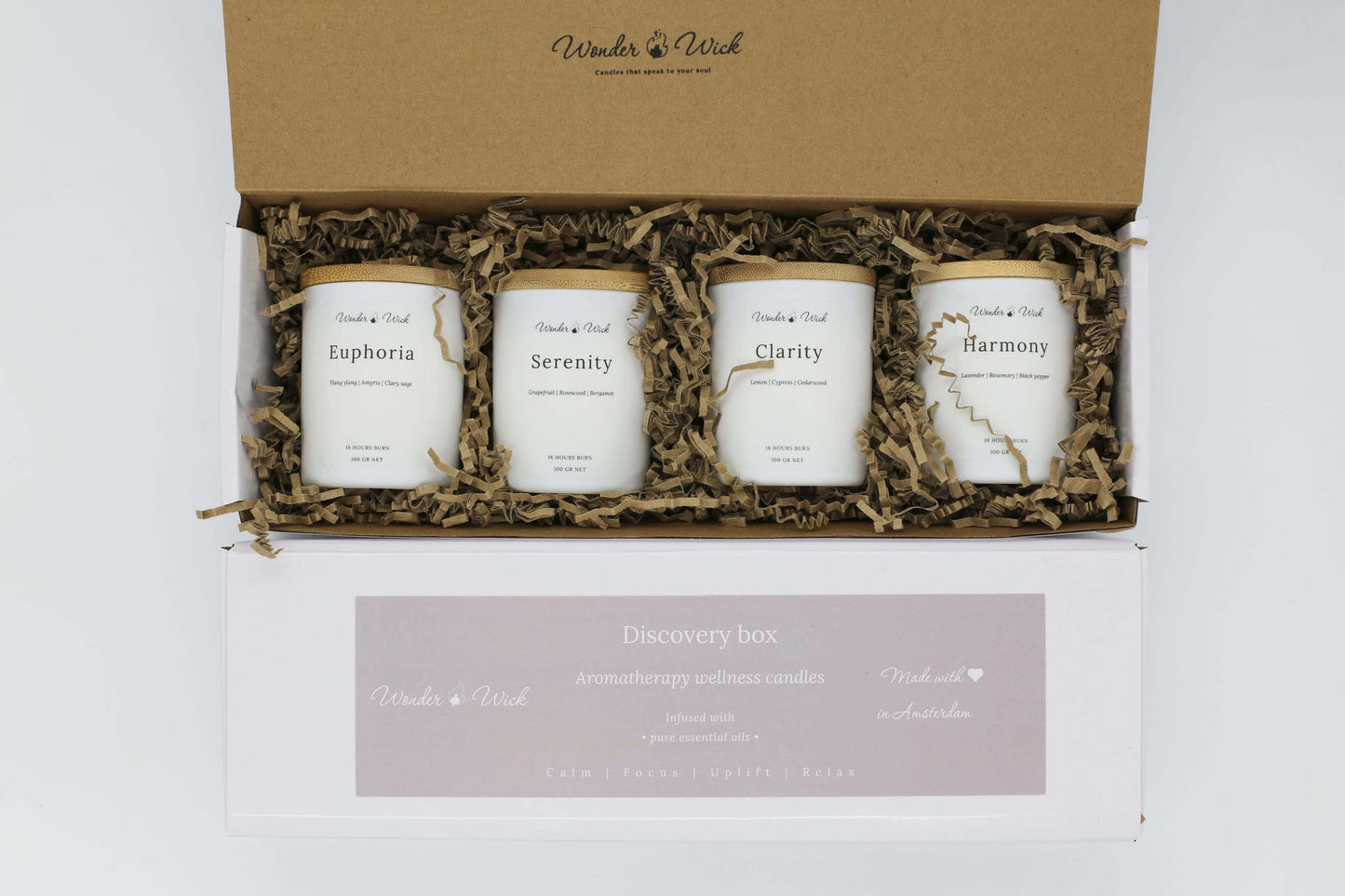 Close-up of Wonder Wick discovery box with four essential oil candles, including Euphoria, Serenity, Clarity, and Harmony, packed with biodegradable brown paper.