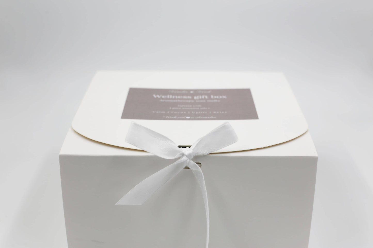 Wonder Wick Wellness Gift Box for aromatherapy wax melts, closed with a tied white ribbon. The gray label features 'Wellness gift box - Aromatherapy wax melts,' with benefits 'Calm, Focus, Uplift, Relax,' indicating a thoughtful gift.