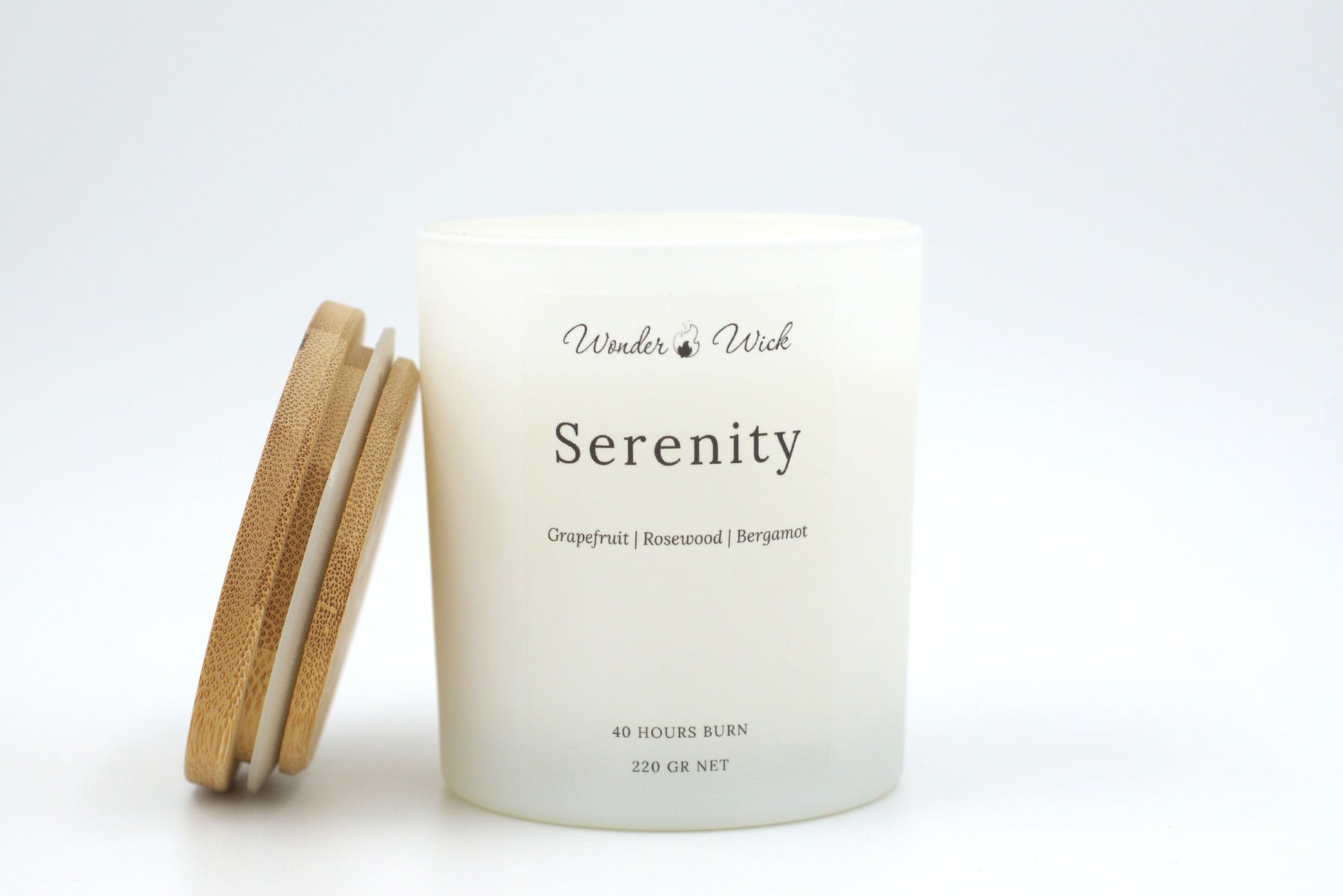 Serenity candle 220g with bamboo lid resting beside, highlighting uplifting scent of grapefruit, bergamot, and rosewood.