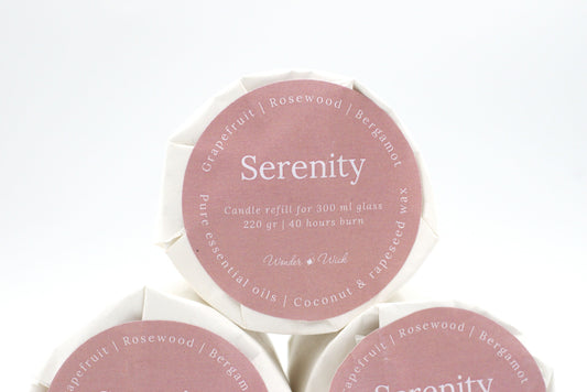 Serenity candle refill for 300 ml glass with 40 hours burn time, wrapped in eco-friendly packaging with a label showing grapefruit, rosewood, and bergamot essential oils.