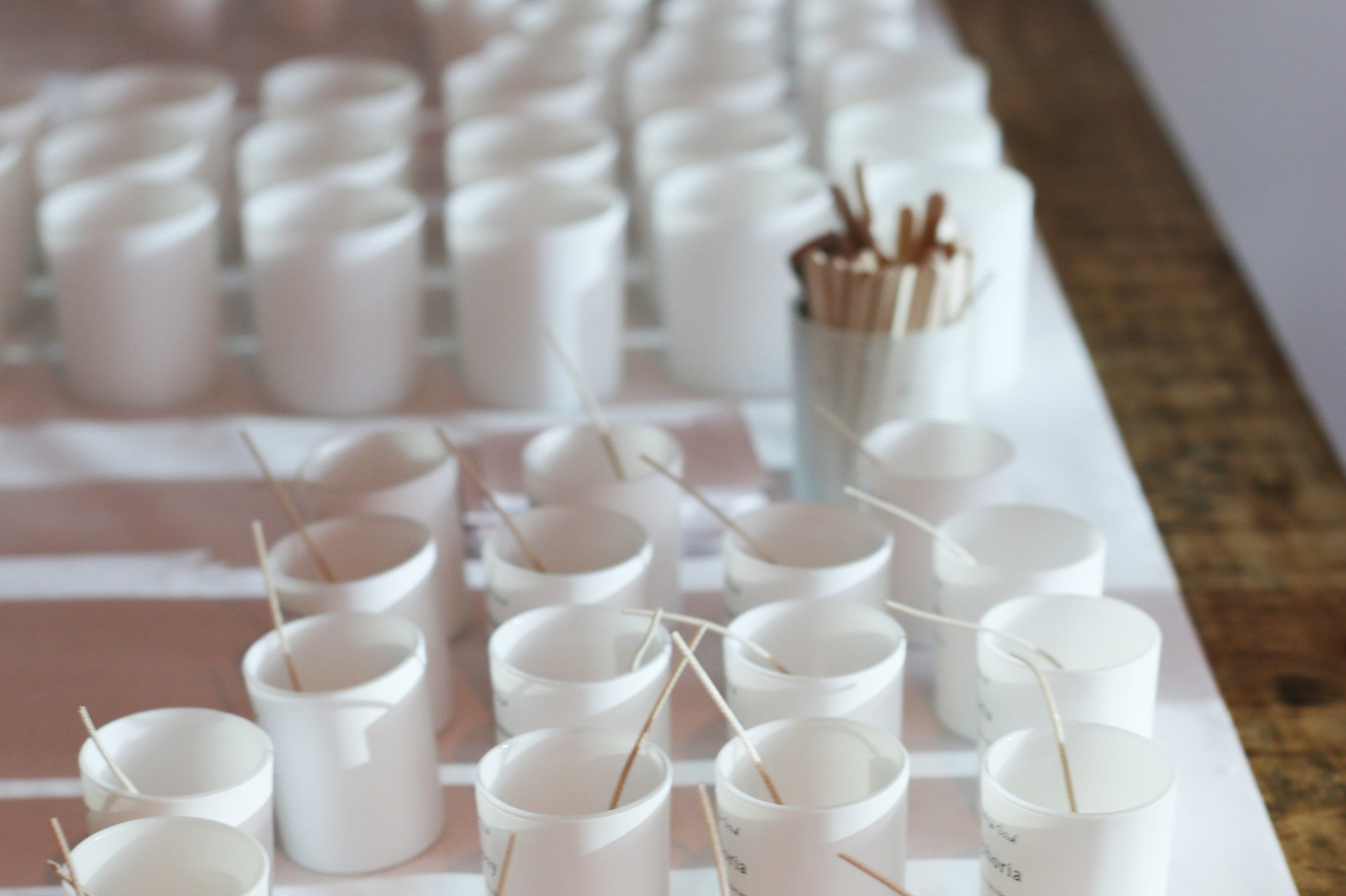 Rows of candle jars with wicks set up for pouring in a small-batch candle studio, showcasing the handcrafted process behind Wonder Wick candles.